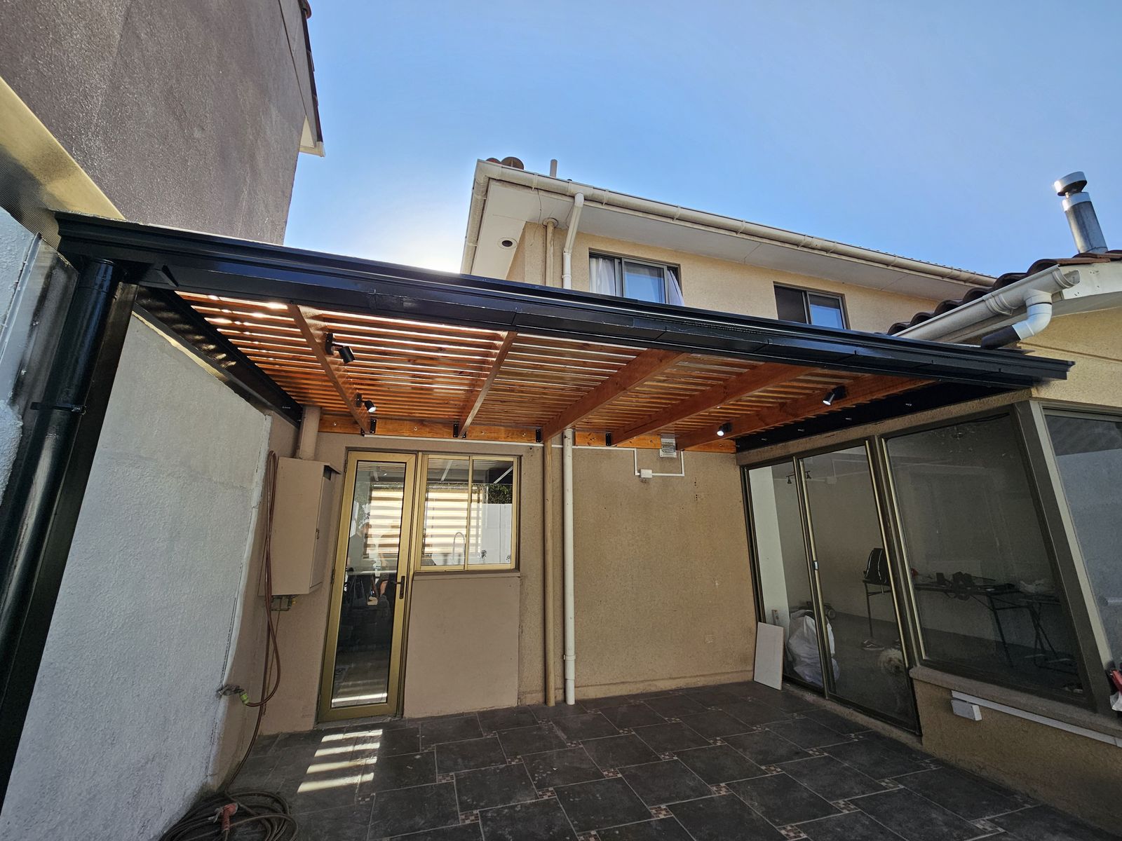Pérgola metálica con techo de madera en un patio